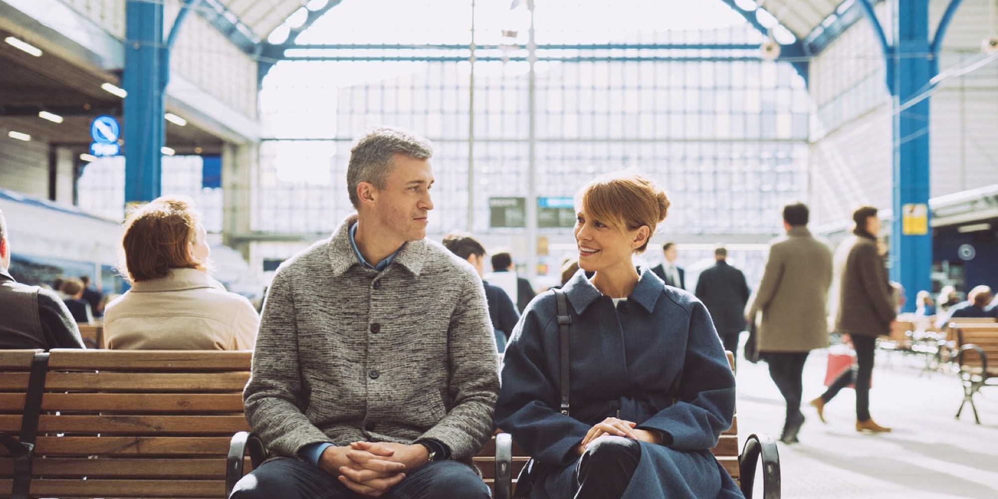 Two colleagues on a station bench weighing one job offer against another before the train leaves