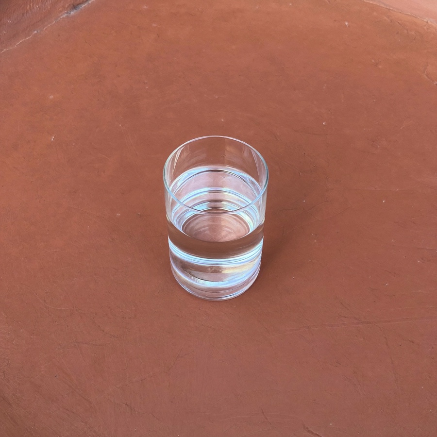 A single glass of water on terracotta plaster, a small first step in recovery from burnout