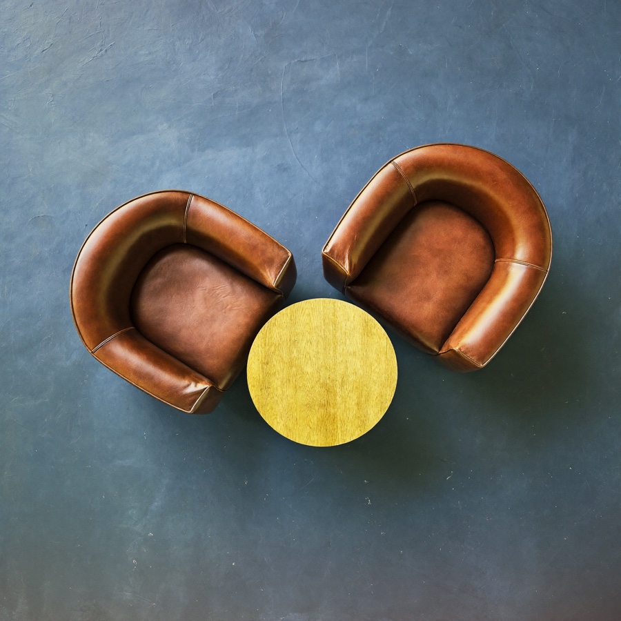 Two leather armchairs and a round oak table, set out for a conversation before a decision