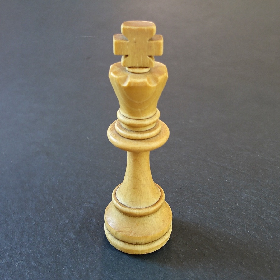A wooden chess king on slate, the piece the whole board is arranged around