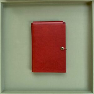 A closed red leather journal, where a set of written principles starts