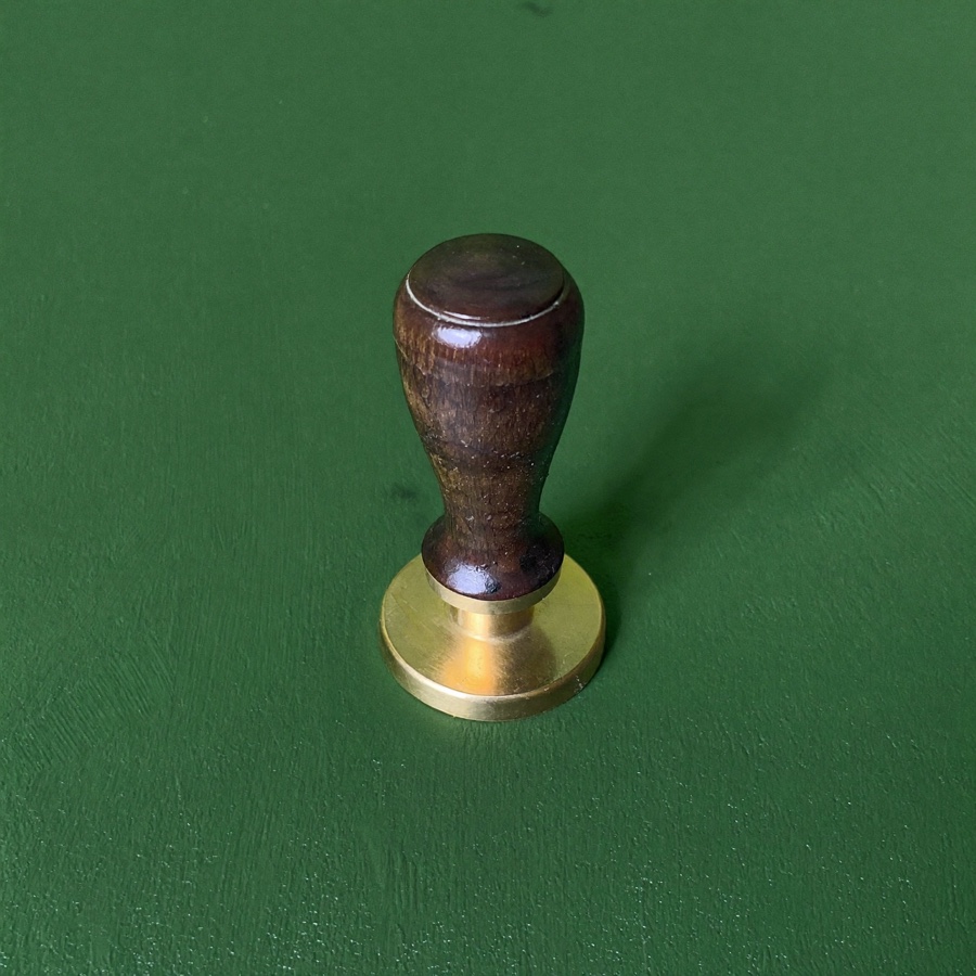 A brass wax seal stamp on green plaster, the mark of a salary negotiation email sent once and sent properly