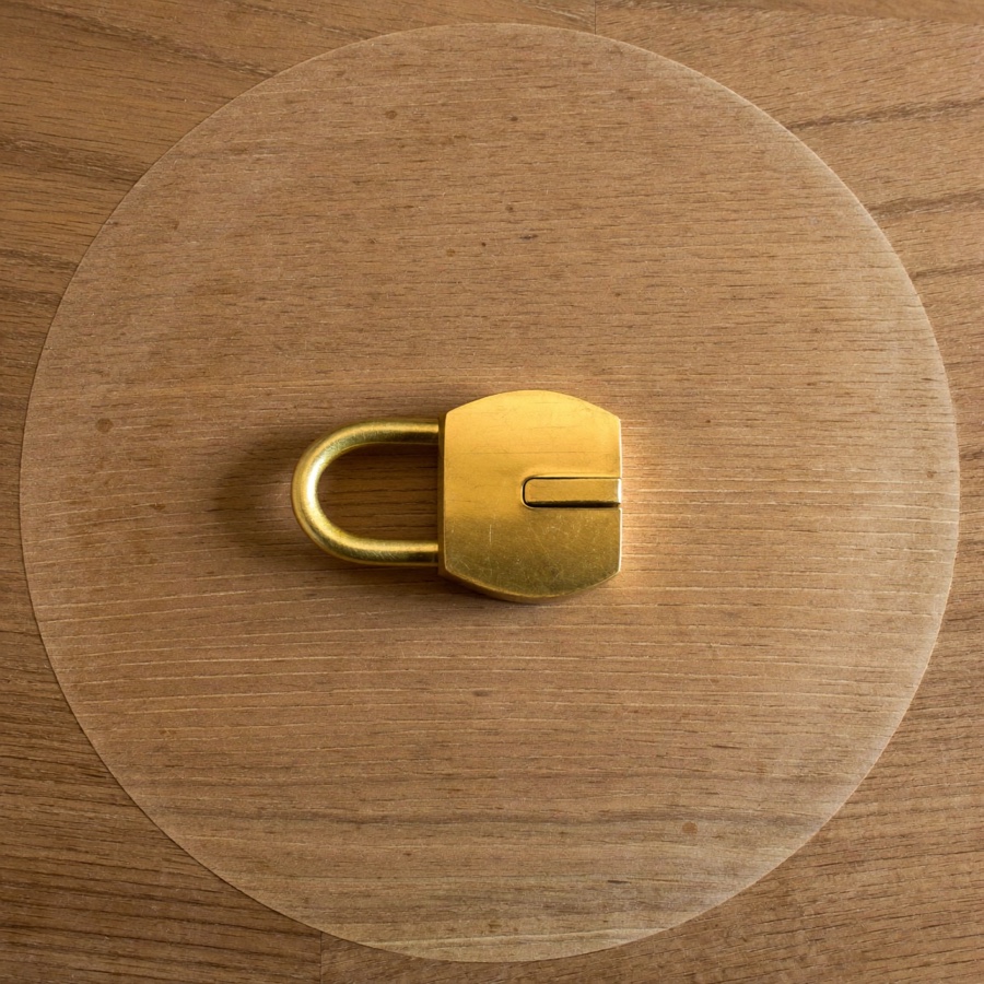 A small brass padlock on oak, for an article on a Roth IRA vs brokerage account and which money to lock away