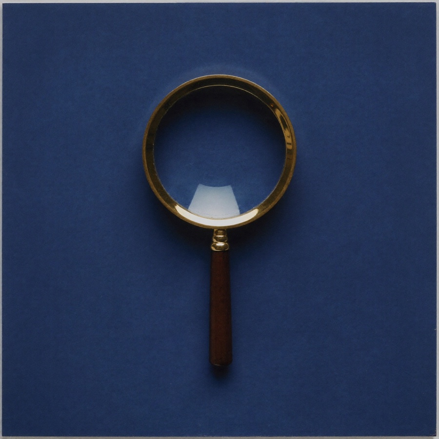A brass magnifying glass on blue plaster, for an article on critical thinking exercises for executives