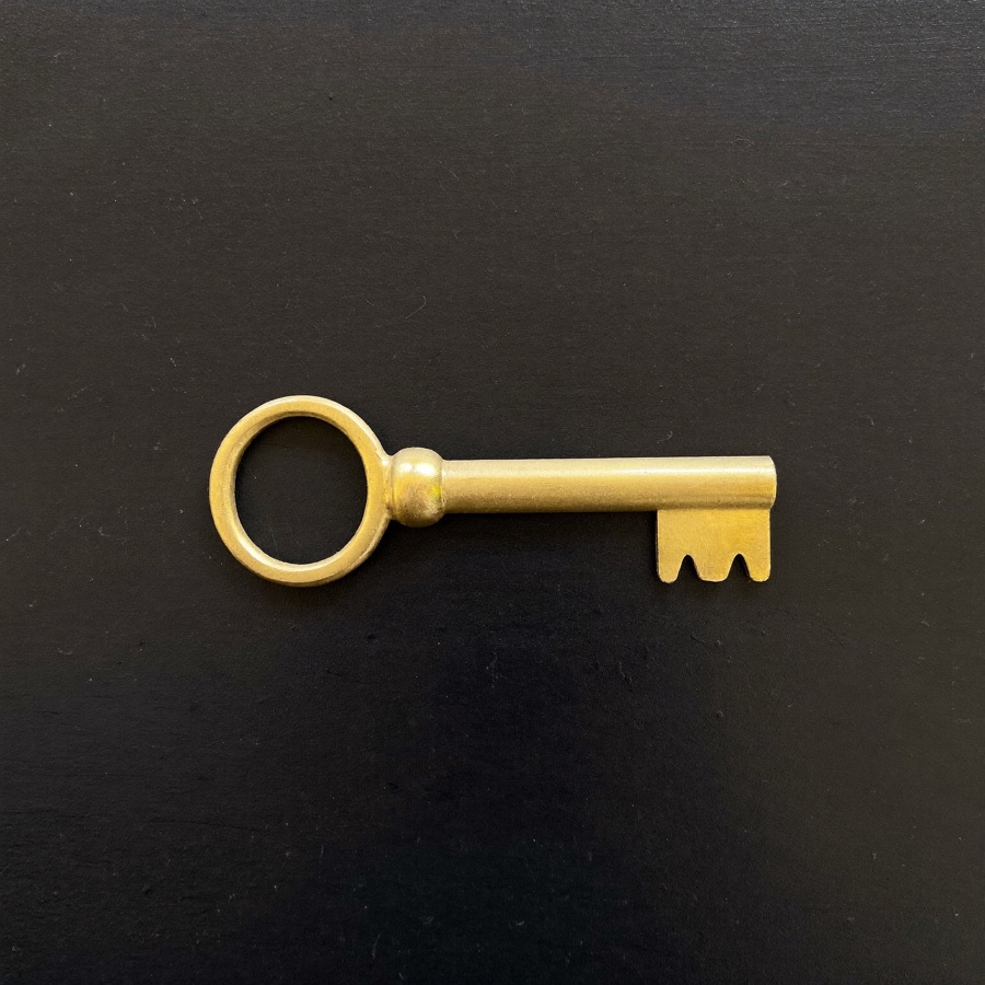 A brass door key on black wood, for an article on how to start a consulting business