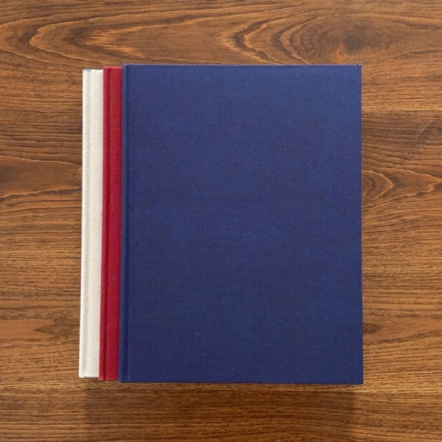 A stack of plain hardback books on an oak desk, for an article on the Warren Buffett books worth reading